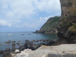 a rocky shore with two boats in the water at casa vacanze di antonia in Procida