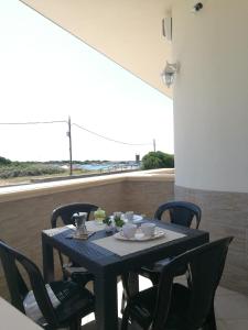 un tavolo e sedie su un balcone con vista di Cala del Conte 3 a Torre Colimena