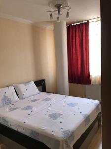 1 dormitorio con 1 cama y una ventana con cortina roja en Bolero Hotel, en Ferizaj