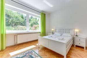 - une chambre avec un lit blanc et une grande fenêtre dans l'établissement Gdynia Comfort Apartments Perkuna, à Gdynia