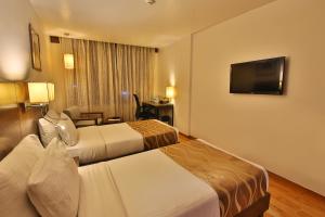 a hotel room with two beds and a flat screen tv at Ginger Vadodara ,Alkapuri in Vadodara +58 photos