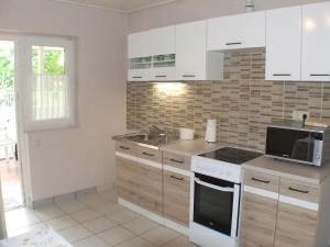 a kitchen with white cabinets and a sink at Nika nyaraló jakuzzival in Balatonkeresztúr +14 photos