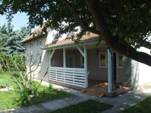 ein weißes Haus mit einer Veranda und einem Baum in der Unterkunft Nika nyaraló jakuzzival in Balatonkeresztúr