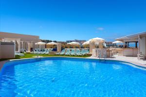 a large swimming pool with chairs and umbrellas at Aparthotel Los Dragos del Sur in Puerto de Santiago
