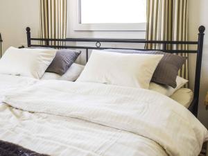 uma cama com lençóis brancos e almofadas num quarto em Ferienwohnung im Weiler em Winterlingen
