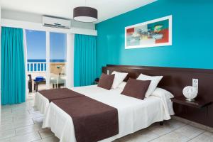 a bedroom with a large bed with blue walls at Aparthotel Los Dragos del Sur in Puerto de Santiago
