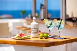 a table with two glasses and a bottle of alcohol at Aparthotel Los Dragos del Sur in Puerto de Santiago