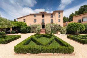 ein Haus mit einer Hecke inmitten eines Gartens in der Unterkunft Can Mora de Dalt in Sant Vicenç de Montalt