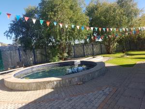 einen kleinen Pool in einem Backsteinhof mit einer Reihe von Flaggen in der Unterkunft New Rush Guest House in Kimberley