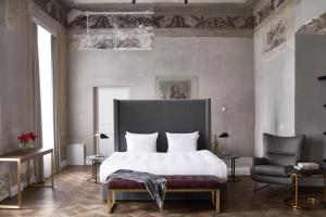 a bedroom with a large bed and a chair at Hotel Pacai, Vilnius, a Member of Design Hotels in Vilnius