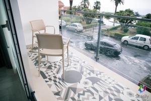 balcón con sillas y vistas a un aparcamiento en Seasily - B&B yourself, en Zafferana Etnea