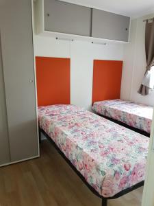 MontorfanoにあるCamping Montorfanoのオレンジと白の壁の客室で、ベッド2台が備わります。