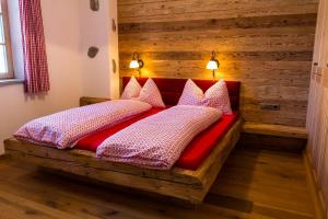 a wooden bed with pillows on it in a room at Apperlehof in Villabassa