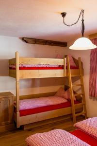 2 Etagenbetten in einem Zimmer mit einer Lampe in der Unterkunft Apperlehof in Niederdorf