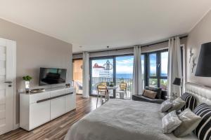 Apartament Prestige & Sea Horyzont 613 في مينززدرويه: غرفة نوم بسرير وتلفزيون وغرفة معيشة