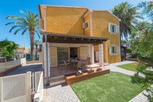 a yellow house with a yard with a patio at Pereta in Port d'Alcudia