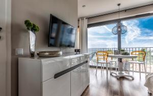 a living room with a television and a table with chairs at Apartament Prestige & Sea Horyzont 613 in Międzyzdroje
