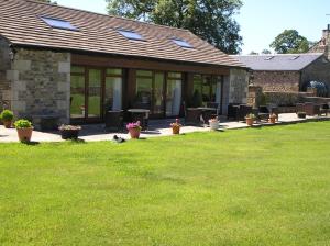 una casa con un patio con mesas y macetas en Green Grove Country House, en Malham