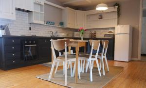 cocina con mesa, sillas y nevera en Rosaries Apartment Kilkee, en Kilkee