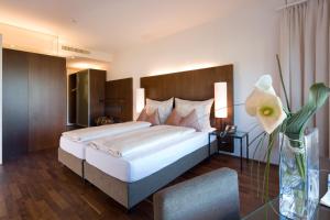 a bedroom with a large bed and a vase with a flower at Hotel Penz West in Innsbruck