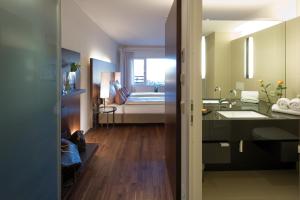 a bathroom with a sink and a bedroom with a bed at Hotel Penz West in Innsbruck