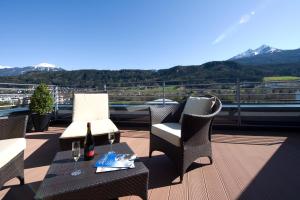a balcony with chairs and a table with a bottle of wine at Hotel Penz West in Innsbruck