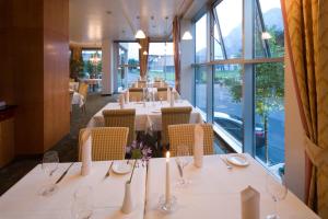 a restaurant with white tables and chairs and windows at Hotel Penz West in Innsbruck