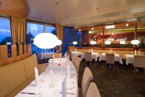a restaurant with white tables and chairs and windows at Hotel Penz West in Innsbruck