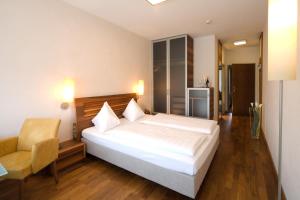 a bedroom with a large white bed and a chair at Hotel Penz West in Innsbruck