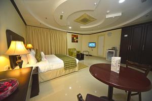 a hotel room with a bed and a table at Alain Hotel Ajman in Ajman 