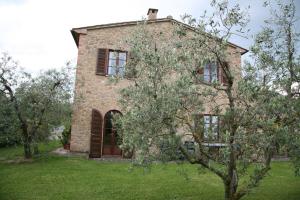 une maison en pierre avec un arbre en face de celle-ci dans l'établissement Il Fornello, à Volterra
