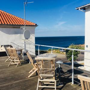 une terrasse avec des chaises et une table et l'océan dans l'établissement Badepensionat Sandloppen, à Allinge-Sandvig