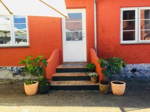 une maison rouge avec des escaliers et des plantes en pot devant elle dans l'établissement Badepensionat Sandloppen, à Allinge-Sandvig