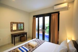 Schlafzimmer mit einem Bett, einem Spiegel und einem Fenster in der Unterkunft Nyoman Villa Sanur in Sanur
