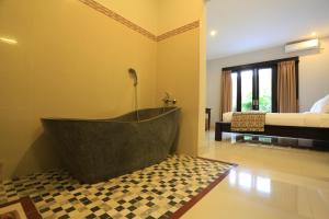 ein Bad mit einer Badewanne in der Ecke eines Zimmers in der Unterkunft Nyoman Villa Sanur in Sanur