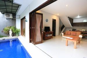 ein Wohnzimmer mit einem Pool neben einem Haus in der Unterkunft Nyoman Villa Sanur in Sanur
