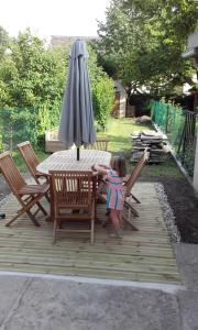 Une petite fille debout à une table en bois avec un parasol dans l'établissement Chez Henriette, à Voiteur