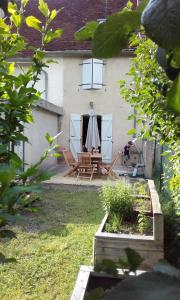 ein Haus mit einer Terrasse mit einem Tisch und einem Sonnenschirm in der Unterkunft Chez Henriette in Voiteur