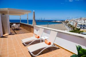 a balcony with white chairs and a view of a beach at Viviendas Vacacionales Amanay in Gran Tarajal