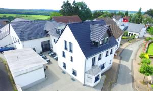 una vista aérea de una casa blanca con techo negro en Fast Lane Hotel en Barweiler