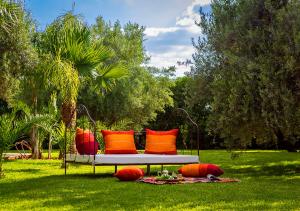 a bench with orange and red pillows on the grass at VILLA PASCHMINA PISCINE CHAUFFEE in Ourika