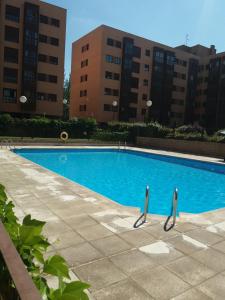 duży niebieski basen z budynkami w tle w obiekcie My Suites Madrid - Aeropuerto Ifema w Madrycie