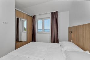 a bedroom with two beds and a window at Apartmani Daniela Podgora in Podgora