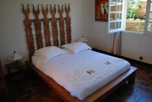 a bed with a wooden headboard in a bedroom at Appartements d'Hôtes Marciloui in Antsirabe
