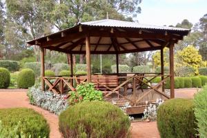 un cenador de madera con un banco en un jardín en Travellers Rest Motel, en Mundaring