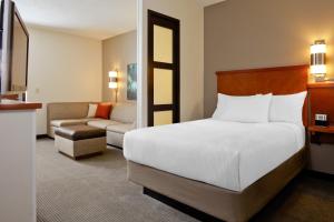 a hotel room with a bed and a couch at Hyatt Place Orlando Airport in Orlando