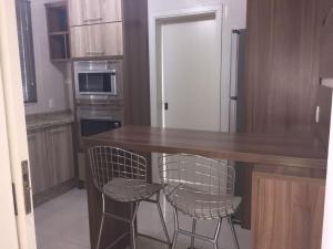 eine Küche mit einem Holztisch und 2 Stühlen in der Unterkunft Apartamento em condominio fechado Bento Goncalves in Bento Gonçalves