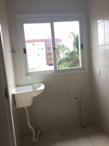 ein weißes Waschbecken im Bad mit Fenster in der Unterkunft Apartamento em condominio fechado Bento Goncalves in Bento Gonçalves