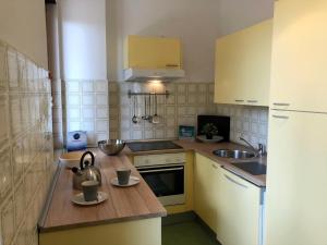 una pequeña cocina con electrodomésticos blancos y armarios amarillos en House Levante by Holiday World, en Pieve Ligure