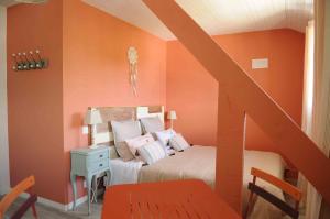 ダムガンにあるLes loges de l'ecurieのオレンジ色の壁のベッドルーム1室、ベッド1台、階段が備わります。